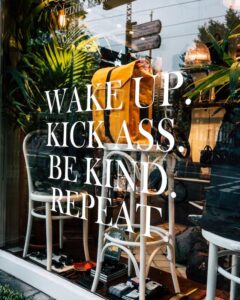 Ett genomskinligt skyltfönster med texten, Wake Up. Kick Ass. Be kind. Repeat. 