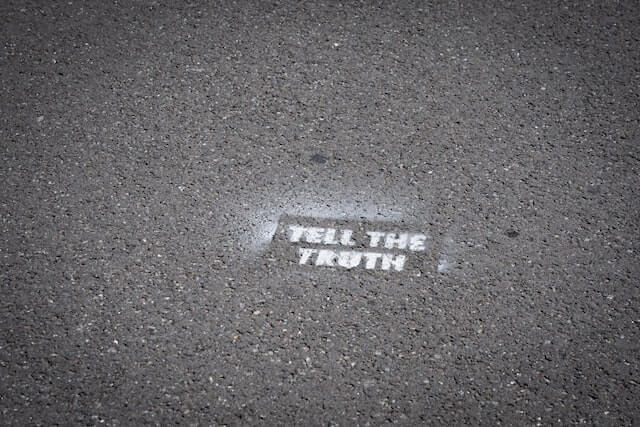 En grå betong väg med vit text där det står Tell The Truth. 
